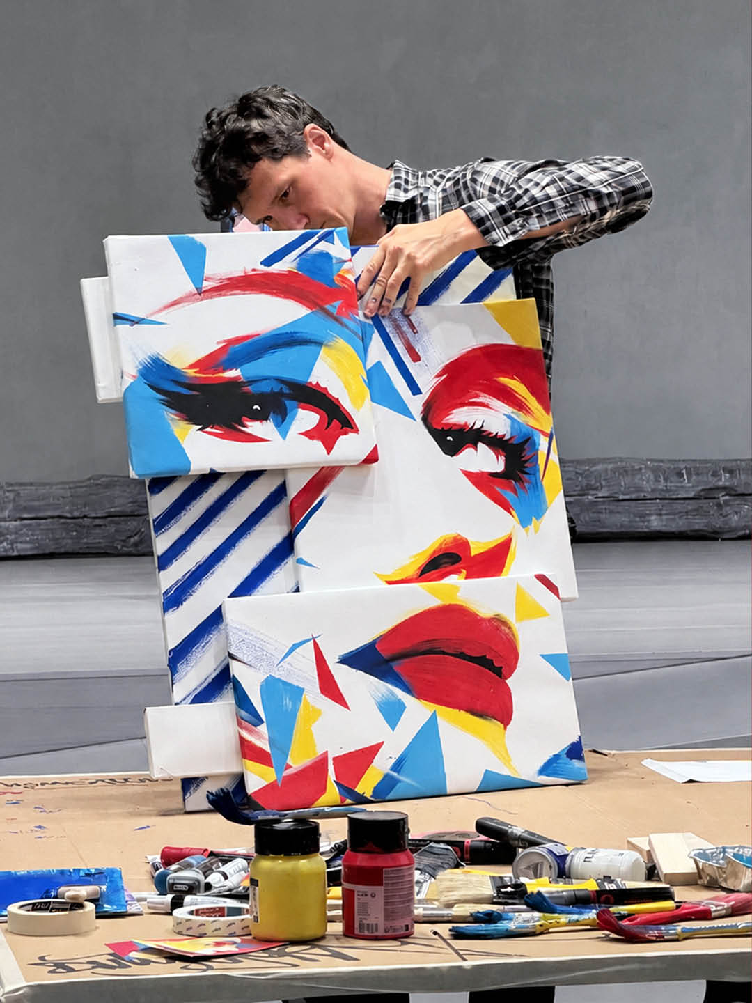 Guido DutyGorn reconstructing Out of the Blue, a deconstructed female portrait painted on multiple canvases in red, blue, yellow and black.